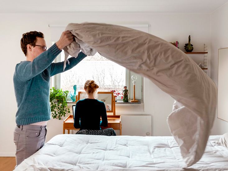 Man-making-bed-while-woman-working-at-table-in-bedroom-732x549-thumbnail