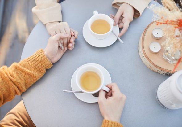 close-up-young-couple-holding-hands-drinking-tea-their-romantic-date-restaurant_249974-6608