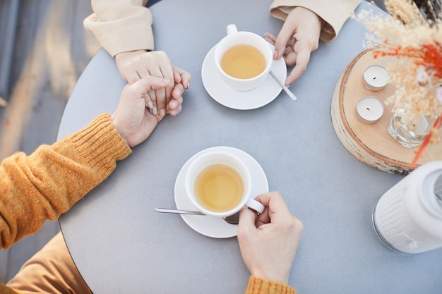 close-up-young-couple-holding-hands-drinking-tea-their-romantic-date-restaurant_249974-6608